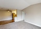 Located at 1401 Lakewood Ave in Modesto, CA, this 2-bedroom, 2-bathroom apartment offers a functional and comfortable single-floor layout. The open living area greets you upon entry, featuring soft carpet underfoot, vaulted ceilings that add a sense of height and airiness, and a ceiling fan for year-round comfort. The kitchen is positioned adjacent to the living space and includes white cabinetry, a stainless steel refrigerator, and a breakfast bar peninsula with wood-tone accents, complemented by hardwood-style flooring that extends through the kitchen and dining area. The spacious primary bedroom features large windows that invite natural light and offer exterior views, along with plush carpeting and vaulted ceilings. The second bedroom is generously sized with neutral carpet and a textured ceiling. Each bedroom is served by its own closet, providing ample storage. The two bathrooms are finished with white cabinetry, stone-tone countertops, and hardwood-style flooring. One bathroom features a walk-in shower with sliding glass doors, while the other offers a full tub-shower combination. Additional storage is available via a built-in shelving closet. Neutral warm-beige tones throughout create a cohesive and inviting ambiance.