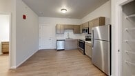 This single-floor, 2-bedroom, 2-bathroom unit offers a practical and modern layout designed to maximize functionality. Light wood-style flooring runs consistently throughout the space, creating a cohesive and clean aesthetic.

The kitchen is well-equipped with stainless steel appliances, including a refrigerator, range, microwave, and dishwasher. Warm taupe cabinetry pairs with light stone-look countertops, providing ample storage and workspace. The kitchen opens directly into the living area, which features a sliding glass door leading to a private balcony, allowing natural light to fill the shared living space.

Both bedrooms are modestly sized with neutral walls, blinds-fitted windows, and dedicated closets with built-in shelving. The primary bedroom includes a sliding closet door for easy access. Each bedroom is served by its own bathroom; one features a single-vanity with warm wood cabinetry and a tub-shower combination, while the second bathroom offers a similarly styled vanity. Both bathrooms include large mirrors with overhead lighting and light wood-style flooring. Two hallways and additional closet space contribute to practical storage throughout the unit.
