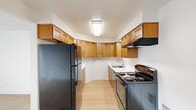Located at 2435 SW Ecole Ave in Beaverton, Oregon, this single-floor, 2-bedroom, 1-bathroom home offers a practical and well-organized layout. Light wood-style flooring flows throughout the main living areas, giving the space a clean, cohesive look. The living room is bright and airy, featuring a textured ceiling, a ceiling fan, and a large window with vertical blinds that allows natural light to fill the room. An in-unit wall AC unit provides climate control. The kitchen is thoughtfully designed with warm wood cabinetry extending to the ceiling, offering generous storage. Black appliances — including a refrigerator, electric range, and range hood — complement the white countertops and light flooring. The open sightline between the kitchen and dining area enhances the sense of space. The bedrooms are comfortable, with the primary bedroom offering a notably spacious footprint. Both bedrooms feature carpet flooring and closets with hanging rods. The home includes four closets in total, providing ample storage throughout. The bathroom is well-appointed with a tub-shower combination, a wide vanity with warm wood cabinetry, white countertop, and a large mirror. A hallway connects the main rooms, contributing to the home's efficient and straightforward floor plan.