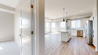This well-appointed 3-bedroom, 2-bathroom residence offers a thoughtfully designed single-floor layout that balances comfort and modern style. The open-concept kitchen and living area serves as the heart of the home, featuring warm hardwood-style flooring, crown molding, and large windows that flood the space with natural light while framing sweeping outdoor views of the surrounding landscape. The kitchen is equipped with stainless steel appliances, a central island with granite countertops, white shaker-style cabinetry with matte black hardware, a classic subway tile backsplash, and stylish pendant lighting overhead. A sliding glass door in the living area opens to a private balcony, extending the living space outdoors and offering scenic views. The bedrooms are carpeted for comfort, with neutral tones creating a calm, restful atmosphere. The primary bedroom is generously sized and includes access to a walk-in closet outfitted with wire shelving systems for organized storage. The bathrooms are clean and functional, with one featuring a full tub-shower combination, wood-look flooring, and gray cabinetry. Throughout the home, a consistent palette of soft neutrals, quality finishes, and abundant natural light contribute to a bright, modern, and welcoming ambiance.