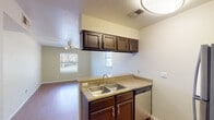 Located at 1200 W 40th Street in Austin, Texas, Unit 105 is a single-floor residence that offers a practical and well-appointed layout. The kitchen serves as a functional centerpiece, featuring dark espresso-toned cabinetry, granite-style countertops, a double stainless steel sink, a stainless steel range, a dishwasher, and a refrigerator. Upper and lower cabinetry provide ample storage, while the open sight line into the living area creates a connected, airy feel. Wood-style flooring flows consistently throughout the unit, lending warmth and visual continuity to each room. The living area is generously sized, bathed in natural light from multiple windows fitted with blinds, and features a ceiling fan with integrated lighting. The bedrooms continue the same flooring and neutral color palette, each equipped with ceiling fans and windows that let in natural light and outdoor views. The bathroom is clean and efficiently designed, complete with dark wood vanity cabinetry, granite-style countertops, a full tub and shower combination with white tile surround, and chrome fixtures and accessories. A dedicated entry area near the kitchen provides a natural transition point into the unit. Overall, the space presents a cohesive, neutral aesthetic suited for comfortable everyday living in central Austin.