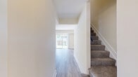 Located at 801 Court Square Dr in Edgewood, MD, this two-story, two-bedroom, two-bathroom home is efficiently laid out across two floors. The main level features a bright, open living room with wood-look flooring and a sliding glass door that fills the space with natural light and provides direct outdoor access. The adjacent kitchen is equipped with light wood cabinetry, dark countertops, a double sink, and white appliances including a range, over-the-range microwave, and refrigerator. A hallway connects the kitchen to the rest of the main level, which also includes a full bathroom featuring a single-sink vanity with wood cabinetry, a tub-shower combination with white tile surround, and tile flooring. A carpeted staircase leads to the upper floor, where both bedrooms are located. The primary bedroom is generously sized and features wood-look flooring and a closet. The second bedroom also features wood-look flooring and multiple windows that bring in natural light. A second full bathroom on the upper level includes a vanity with wood cabinetry and a mirrored medicine cabinet. Neutral wall tones and consistent flooring throughout give the home a clean, cohesive aesthetic.