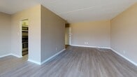 This single-floor residence at 400-402 Foulk Rd in Wilmington, Delaware offers a practical and comfortable layout with thoughtfully updated finishes throughout. The open living area is finished with durable hardwood-style flooring and neutral warm-toned walls, creating a bright and inviting atmosphere. A large sliding glass door fills the living space with natural light and provides access to an outdoor area, offering pleasant views of the surrounding greenery. The kitchen is compact yet well-equipped, featuring stainless steel appliances including an electric range, over-the-range microwave, and dishwasher, complemented by white cabinetry with frosted glass upper panels and a sleek stainless steel sink and backsplash. A hallway connects the living areas to the private spaces, including a carpeted bedroom with a built-in closet featuring bifold doors and a wall-mounted HVAC unit beneath a window with natural views. The bathroom is clean and functional, with a white vanity, integrated sink, a large mirror, and a walk-in shower. A textured ceiling is consistent throughout the unit. The overall design is understated and move-in ready, with a neutral color palette and practical details suited for comfortable everyday living.