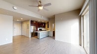 This thoughtfully designed single-floor residence offers a clean, contemporary aesthetic throughout its open-concept layout. The main living area is bright and airy, featuring light hardwood-style flooring, neutral warm-toned walls, and a ceiling fan that enhances comfort. Large sliding glass doors lead to a private balcony, flooding the living space with natural light and providing views of the surrounding area, complemented by an additional side window.

The kitchen is a standout feature, showcasing rich dark-toned cabinetry with sleek hardware, white countertops, and a full suite of stainless steel appliances including a refrigerator, range, and built-in microwave. A central island with an undermount double sink serves as both a functional workspace and a casual gathering point, with pendant lighting adding a polished finishing touch.

The bedroom offers a comfortable retreat with a sliding closet featuring built-in rod storage and a bright window overlooking the exterior. A built-in desk nook provides a dedicated workspace area just off the main living zone.

The bathroom is cleanly finished with dark cabinetry, a white vanity countertop, hardwood-style flooring, a tiled tub-shower combination, and a window for natural ventilation. Throughout the residence, consistent finishes and a cohesive design palette create a unified and functional living environment.