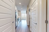 Located at 1223 East Plant Street in Winter Garden, FL, this thoughtfully designed one-bedroom, one-bathroom unit makes excellent use of its compact footprint across a single floor. The open-concept kitchen and living area serves as the heart of the home, featuring wood-style flooring, recessed lighting, and a bright window that draws in natural light. The galley-style kitchen is well-appointed with white shaker cabinetry, open shelving, a marble-look tile backsplash, stainless steel appliances including a refrigerator, range, microwave, and dishwasher, and a matte black faucet over an undermount sink with light quartz countertops. A hallway connects the main living area to the private bedroom, which offers light hardwood-style flooring, a ceiling fan, and multiple windows with views of the surrounding neighborhood, filling the room with natural light. Two closets provide convenient storage solutions. The bathroom is finished with a white subway tile tub and shower surround, matte black fixtures, a white vanity with quartz countertops, and wood-style flooring, creating a clean, contemporary aesthetic. A dedicated laundry area adds further practicality. The unit's neutral palette and modern finishes create a cohesive, move-in-ready living environment.