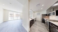 Located at 5315 E High St in Phoenix, AZ, this modern 2-bedroom, 2-bathroom residence offers a thoughtfully designed single-floor layout with clean lines and contemporary finishes throughout. Light-toned hardwood-style flooring runs seamlessly across the entire space, complementing the crisp white walls and creating a bright, cohesive aesthetic.

The galley-style kitchen is a standout feature, showcasing dark espresso cabinetry with brushed nickel hardware, white quartz countertops, stainless steel appliances including a gas range, built-in microwave, refrigerator, and dishwasher, along with stylish pendant lighting that adds a refined touch.

The open living area is bathed in natural light from large floor-to-ceiling sliding glass doors that lead to a private balcony, offering views of the surrounding urban landscape. Both bedrooms are generously proportioned, with the primary bedroom featuring ample natural light and access to a dedicated walk-in closet outfitted with multi-tiered shelving and hanging rods. Each bathroom is finished with clean white tile, a soaking tub and shower combination, and dark vanity cabinetry consistent with the home's modern design language. Recessed lighting throughout enhances the space's polished, contemporary ambiance.