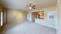 This single-floor residence offers a thoughtfully designed layout with a warm, neutral color palette and plush carpeting throughout the main living and sleeping areas. The open-concept living room is generously proportioned, featuring a ceiling fan with light fixture, track lighting, and multiple windows plus a door that invite ample natural light. It connects seamlessly to the kitchen via a pass-through counter with pendant lighting, creating an ideal space for entertaining.

The kitchen is well-equipped with light wood cabinetry, light-toned countertops, stainless steel appliances including a range, over-the-range microwave, refrigerator, and double-basin sink — all set on easy-care tile flooring.

The residence includes multiple bedrooms, each finished with soft carpeting, ceiling fans, and windows fitted with blinds for natural light and privacy. One bedroom features corner windows for added brightness and openness.

Two full bathrooms serve the home, each featuring a tub-shower combination with decorative tile accents, wood-toned vanity cabinetry, and light tile flooring. The primary bathroom includes a well-lit vanity with a marble-style countertop and a large mirror. The warm yellow accent walls in the bathrooms add a welcoming touch to the overall ambiance of this comfortable and functional home.