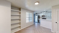 Located at 6000 Oakmont Trail in Fort Worth, TX, this one-bedroom, two-bathroom unit offers a thoughtfully designed single-floor layout that maximizes every square foot. Throughout the space, light-toned herringbone-patterned flooring creates a visually striking foundation that ties the rooms together seamlessly.

The open living area connects directly to the kitchen and features built-in wall shelving, ideal for display or storage, along with a window that allows natural light to brighten the space. The kitchen is well-appointed with white cabinetry accented by matte black hardware, stainless steel appliances including a refrigerator, range, microwave, and dishwasher, a white quartz countertop peninsula, and a stylish black pull-down faucet over the undermount sink. Track lighting overhead adds a modern touch.

The bedroom is a comfortable retreat, featuring multiple windows that invite natural light, a ceiling fan, and a sliding closet. Both bathrooms are clean and functional — one includes a tub-shower combination with white subway tile surround, while the other features a vanity with a quartz countertop, matte black fixtures, and a mirror. The textured ceilings are consistent throughout, adding a classic finish to this efficient and well-updated unit.
