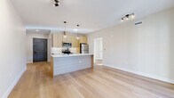 This thoughtfully designed 2-bedroom, 2-bathroom residence in Brookfield, CT offers a clean, modern aesthetic carried consistently throughout its single-floor layout. Light-toned hardwood flooring flows seamlessly across the open-concept living, dining, and kitchen area, creating a bright and cohesive atmosphere. The kitchen is a standout feature, showcasing light wood cabinetry, white quartz countertops, a white subway tile backsplash, and a full suite of stainless steel appliances. A central island with a matte black sink and pendant globe lighting above serves as both a functional workspace and a natural gathering point. The living area is generously proportioned and connects directly to an outdoor space via a black-framed glass sliding door. Both bedrooms are well-lit, with black-framed windows inviting abundant natural light and outdoor views. The primary bedroom is spacious with a dedicated closet. Each bathroom features light wood vanities with white countertops, large-format tile flooring, and glass-enclosed walk-in showers with floor-to-ceiling tile surround. A dedicated in-unit laundry room with a full-size washer and dryer adds everyday convenience. The space offers a fresh, move-in-ready feel with a neutral palette and modern hardware throughout.