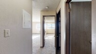 Located at 2300 E 18th St in Casper, Wyoming, this one-bedroom, one-bathroom unit offers a practical and well-organized single-floor layout. The living area features plush carpeting, textured ceilings, and natural light streaming through a window, creating a warm and inviting atmosphere. A half-wall pass-through connects the living space to the kitchen, enhancing the open feel between the two areas. The kitchen is equipped with warm oak cabinetry offering ample storage, white appliances including a coil-top electric range and dishwasher, a double basin sink, and light-colored countertops, all set on tile flooring. The bedroom is a comfortable, well-proportioned room with soft carpeting, baseboard heating, a wall-unit air conditioner, and a window that frames views of the surrounding landscape. A dedicated closet provides convenient storage. The bathroom features tile flooring, a full tub-shower combination with a white surround, a vanity with a mirrored medicine cabinet, and overhead lighting. A carpeted hallway connects the rooms, providing a cohesive flow throughout the unit. This home offers a straightforward, functional living environment well-suited for Casper's climate.