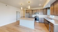 This single-floor home on Daylight Dr in Sioux Falls, South Dakota, presents a well-designed layout with modern finishes and a bright, open atmosphere. The kitchen serves as a central highlight, featuring rich dark-stained cabinetry with gold hardware, a large center island with light countertops, and a full suite of stainless steel appliances including a refrigerator, electric range, and built-in microwave. Gold pendant lights hang above the island, adding a contemporary accent. Light hardwood-style flooring flows through the kitchen and living area, where sliding glass doors invite natural light and provide direct outdoor access with views of the surrounding green space.

Bedrooms are carpeted for comfort and include windows that bring in natural light. A dedicated walk-in closet features wire shelving for organized storage. The bathroom is finished with a dark wood vanity, light countertop, framed mirror, and matte black fixtures, maintaining a cohesive modern aesthetic. A separate laundry room accommodates a full-size washer and dryer with overhead wire shelving. The overall design is clean, neutral, and move-in ready.