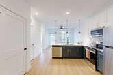 Located at 2291 Mercantile St in Castle Rock, CO, this thoughtfully designed one-bedroom, one-bathroom residence offers a clean, modern aesthetic throughout. The open-concept kitchen and living area serves as the heart of the home, featuring light wood-tone flooring, recessed lighting, and a ceiling fan. The kitchen is outfitted with two-tone cabinetry — crisp white upper cabinets with gold hardware paired with deep charcoal-green lower cabinets — complemented by a white quartz peninsula with an undermount sink, stylish black pendant lights, a hexagonal tile backsplash, and a full suite of stainless steel appliances including a range, microwave, refrigerator, and dishwasher. The bedroom is bright and airy, bathed in natural light through large windows with views of the surrounding Castle Rock neighborhood. Three closets provide generous storage throughout the unit. The bathroom showcases warm wood-look tile walls, a soaking tub, a separate glass-enclosed shower, wood-tone flooring, and a navy vanity with gold hardware topped by an illuminated mirror. Additional conveniences include a dedicated laundry space, a utility room, and a private balcony — completing this well-appointed, move-in-ready residence.
