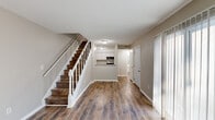 Located at 2415 Brierwood Dr in Albany, Georgia, this two-story home offers four bedrooms and three bathrooms across two thoughtfully laid-out floors. The main level greets you with warm wood-look flooring that extends throughout, creating a cohesive and inviting atmosphere. An open view from the entry reveals a staircase with dark wood treads and a classic white balustrade, leading the eye toward the kitchen, which features white cabinetry and a functional pass-through counter with a built-in range. The main level is completed by hallways and closet space that provide practical storage solutions. Upstairs, the four bedrooms are finished in neutral warm tones with the same durable wood-look flooring, and several rooms feature louvered closet doors. The primary bedroom offers a comfortable, well-proportioned retreat. The three bathrooms are clean and efficiently designed, featuring white vanities with brushed nickel fixtures, large mirrors, and a combination tub-and-shower setup. Textured ceilings add subtle character throughout, while the neutral color palette and consistent finishes provide a move-in ready aesthetic. The home's efficient two-story design maximizes every square foot, making it a practical and comfortable residence.