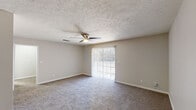 This single-floor, one-bedroom, one-bathroom residence in Hattiesburg, Mississippi, offers a practical and comfortable layout designed for efficient everyday living. The living room is a generously sized, carpeted space featuring a ceiling fan with light fixture and a sliding glass door fitted with vertical blinds, allowing natural light to filter in while providing access to the outdoors. A pendant light fixture marks the transition into the dining area, which connects seamlessly to the kitchen. The kitchen is thoughtfully designed with crisp white cabinetry, light speckled countertops, a double stainless steel sink, wood-look flooring, and stainless steel appliances including a refrigerator and dishwasher. The bedroom is a well-proportioned, carpeted room with a ceiling fan, neutral wall tones, and a window with blinds that brings in natural light. An additional carpeted room, illuminated by an overhead light, provides flexible use as a dining space or secondary living area. The full bathroom features a clean white tub-shower combination with chrome fixtures and overhead cabinetry for added storage. Throughout the residence, textured ceilings, neutral color palettes, and consistent finishes create a cohesive, move-in-ready environment.