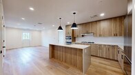 Located at 23–49 Roger Square in Norwalk, CT, this well-appointed 2-bedroom, 2-bathroom residence offers a thoughtfully designed single-floor layout with a clean, contemporary aesthetic. The open kitchen and living area serves as the heart of the home, showcasing warm wood-grain cabinetry that extends floor to ceiling, a generous white quartz island with an integrated sink, stainless steel appliances including a gas cooktop, double wall ovens, and a French-door refrigerator. Pendant lighting adds a refined touch above the island, while light hardwood flooring ties the space together seamlessly. The primary bedroom is a spacious retreat featuring light hardwood floors, recessed lighting, and a window that invites natural light. It is complemented by a dedicated walk-in closet with built-in wire shelving. The second bedroom offers soft carpeting and a bright, airy feel. Both bathrooms are finished in a modern style with large-format tile flooring, dark cabinetry vanities, matte black fixtures, and framed mirrors. One bathroom includes a soaking tub and tiled surround, while the other features an elongated vanity with ample storage. Throughout the residence, crisp white walls, recessed lighting, and a neutral palette create a bright and welcoming atmosphere.