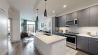 Located at 7557 Main St in Houston's vibrant Texas Medical Center neighborhood, this thoughtfully designed one-bedroom, one-bathroom residence offers a contemporary open-concept layout across a single floor. The combined kitchen and living area serves as the heart of the home, anchored by a striking white quartz waterfall island with an undermount sink and seating for casual dining. The kitchen is outfitted with dark gray flat-front cabinetry reaching to the ceiling, a geometric tile backsplash, and a full suite of stainless steel appliances including a refrigerator, range, and built-in microwave. Sleek pendant lighting adds a modern finishing touch overhead. The living area flows naturally from the kitchen, featuring hardwood-style flooring, a ceiling fan, and floor-to-ceiling windows that open to a private balcony with open city views, filling the space with abundant natural light. The bedroom is a serene retreat with large windows, plush carpeting, a ceiling fan, and a dedicated closet. The well-appointed bathroom features marble-look tile flooring, gray vanity cabinetry with a quartz countertop, a large mirror, and a glass-enclosed walk-in shower. A hallway connects all areas, completing this efficient and stylish urban residence.