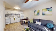 This well-appointed single-floor residence offers a thoughtful layout that maximizes comfort and functionality. The open-concept living area flows seamlessly into the kitchen, creating a cohesive and inviting space. Light wood-style flooring extends throughout, complemented by neutral wall tones that lend a clean, airy ambiance. Ceiling fans are featured in the living area and bedrooms, enhancing airflow and comfort.

The kitchen is outfitted with white cabinetry, white appliances including a range, refrigerator, and dishwasher, and a stylish mosaic tile backsplash that adds a contemporary touch. A double-basin sink with a modern faucet anchors the workspace.

The living room is generously proportioned, with a wall-mounted air conditioning unit, a large window that invites natural light, and direct access to the entry door — making the space feel open and connected to the outdoors.

Both bedrooms are comfortably sized, each featuring ceiling fans, wall-mounted air conditioning units, and windows dressed with blinds and curtain panels that allow for natural light and privacy.

The bathroom is clean and functional, featuring a single-sink vanity with white cabinetry, a framed mirror, and a full shower-tub combo with white tile surround. Wood-style flooring carries through here as well, tying the home together with a consistent, modern aesthetic.