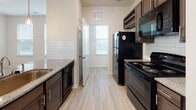 Located at Hanahan Road in North Charleston, South Carolina, this single-floor unit features a thoughtfully designed open-concept layout that seamlessly connects the kitchen and living area. The kitchen is outfitted with dark cabinetry, granite countertops, a subway tile backsplash, light hardwood-style flooring, and black stainless appliances including a refrigerator, range, microwave, and dishwasher. A peninsula with pendant lighting and a built-in sink serves as both a functional workspace and a natural divider between the kitchen and the expansive carpeted living room, which is brightened by multiple windows with blinds and a ceiling fan with light. French doors in the living area provide additional natural light and outdoor access. The bedrooms are carpeted and generously sized, each featuring ceiling fans and large windows that offer views of the surrounding neighborhood. A spacious walk-in closet with wire shelving provides ample storage. The bathrooms are finished with granite-topped dark vanities, hardwood-style tile flooring, and a tiled tub-shower combination. A separate water closet adds an extra layer of privacy in the primary bath. The unit presents a clean, neutral palette throughout, creating a bright and functional living environment.