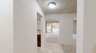 Located at 1059 Wood Duck Ave in Santa Clara, California, this single-story, three-bedroom, two-bathroom home offers a practical and comfortable layout. The combined kitchen and living room serves as the heart of the home, with the kitchen featuring rich dark wood cabinetry, light countertops, tile flooring, and a built-in breakfast bar. The living area flows naturally toward large sliding glass doors that invite natural light and provide views of the outdoor surroundings. A textured ceiling and a baseboard heating unit are consistent throughout the main living spaces. The three bedrooms are carpeted and well-proportioned, with the spacious primary bedroom offering generous room to accommodate various furniture arrangements. Each bedroom benefits from windows that bring in natural light and outdoor views of the surrounding greenery. The two full bathrooms are finished in neutral tones, each featuring a single-sink vanity with ample cabinet storage. One bathroom includes a tub-shower combo with sliding glass doors, while the other offers a standalone shower. A central hallway connects the bedrooms and bathrooms, contributing to an efficient and easy-to-navigate floor plan. Throughout the home, light-toned walls and carpeting create a clean, neutral aesthetic.