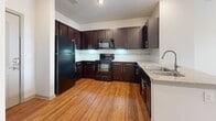 Located at 5610 Glenridge Dr NE in Sandy Springs, GA, this one-bedroom, one-bathroom residence offers a well-organized single-floor layout designed for efficient everyday living. The kitchen is a standout feature, showcasing rich dark espresso cabinetry that extends to the ceiling for ample storage, granite-style countertops, black appliances including a refrigerator, range, and built-in microwave, and warm hardwood flooring that adds a polished, inviting feel. The open layout of the kitchen flows naturally into the living areas. The bedroom is comfortably sized, finished with plush wall-to-wall carpeting, and features a ceiling fan for year-round comfort. A large window with blinds allows natural light to fill the room. The bathroom is well-appointed with tile flooring, a dark-cabinetry vanity with a white countertop and single sink, and a large mirror. It connects directly to a dedicated walk-in closet, complete with built-in shelving and hanging space for organized storage. The overall aesthetic of the unit is clean and neutral, with light walls throughout that create a bright and airy ambiance. This thoughtfully laid-out space offers practical comfort in a desirable Sandy Springs location.