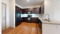 Located at 5610 Glenridge Dr NE in Sandy Springs, GA, this one-bedroom, one-bathroom residence offers a well-organized single-floor layout designed for efficient everyday living. The kitchen is a standout feature, showcasing rich dark espresso cabinetry that extends to the ceiling for ample storage, granite-style countertops, black appliances including a refrigerator, range, and built-in microwave, and warm hardwood flooring that adds a polished, inviting feel. The open layout of the kitchen flows naturally into the living areas. The bedroom is comfortably sized, finished with plush wall-to-wall carpeting, and features a ceiling fan for year-round comfort. A large window with blinds allows natural light to fill the room. The bathroom is well-appointed with tile flooring, a dark-cabinetry vanity with a white countertop and single sink, and a large mirror. It connects directly to a dedicated walk-in closet, complete with built-in shelving and hanging space for organized storage. The overall aesthetic of the unit is clean and neutral, with light walls throughout that create a bright and airy ambiance. This thoughtfully laid-out space offers practical comfort in a desirable Sandy Springs location.