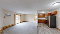 Located at 2061 McKnight Road North in North Saint Paul, MN, this single-floor, 2-bedroom, 1-bathroom unit offers a functional and comfortable layout with consistent warm-toned finishes throughout. The open-concept living room and kitchen area forms the heart of the space, with plush gray carpeting in the living area transitioning to light wood-look flooring in the kitchen. A sliding glass door in the living room provides access to a private balcony, allowing natural light to fill the space. The kitchen features warm honey-toned wood cabinetry, granite-look countertops, a stainless steel refrigerator and range, and ample upper and lower cabinet storage. Both bedrooms are comfortably sized, carpeted, and equipped with closets — the primary bedroom includes a spacious reach-in closet with a rod and shelving. Each bedroom benefits from natural light via windows with horizontal blinds. The full bathroom offers a tub-shower combination with classic white and blue tile surround, a vanity with storage, and wood-look flooring. Baseboard heating runs throughout the unit. The overall aesthetic is clean and neutral, providing a versatile canvas for a variety of living styles.