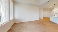 This 1,150 square foot single-floor residence in North Augusta, SC offers 3 bedrooms, 2 bathrooms, and a well-designed open layout. Light wood-style flooring flows consistently throughout, complementing the crisp white walls and clean modern aesthetic. The kitchen is a standout feature, boasting white shaker cabinets with matte black hardware, quartz countertops, a subway tile backsplash, stainless steel appliances including a refrigerator, range, and over-the-range microwave, and a large center island with pendant lighting and a deep sink. The open living room is bright and airy, featuring a tray ceiling and a glass door with flanking windows that invite abundant natural light and outdoor views. Each of the three bedrooms features light flooring, blinds-fitted windows, and built-in closets with double panel doors. The primary bedroom spans 140 square feet. The two bathrooms are finished with wood-look flooring, white vanity cabinetry, and matte black fixtures. One bathroom features a tiled walk-in glass shower, while the second includes a tiled tub-shower combo. A dedicated closet provides additional storage. The unit's cohesive, neutral palette and modern finishes create a clean and functional living environment.