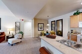 Located at 5082 N Primitivo Way in Fresno, CA, this single-story, 2-bedroom, 2-bathroom residence offers a thoughtfully arranged floor plan that maximizes comfort and functionality. The open-concept living and dining area flows seamlessly from the kitchen, creating a bright, connected space ideal for everyday living and entertaining. The kitchen features warm honey-toned cabinetry, a peninsula with a built-in sink and breakfast bar seating, and white appliances including a range, microwave, and refrigerator. Track lighting and wood-style flooring add a clean, practical finish to the cooking area. The dining space accommodates a full table and is accented by a decorative pendant light and large wall mirrors that enhance the sense of space. The living room benefits from generous natural light streaming through large windows, with soft carpeting throughout. The primary bedroom is comfortably sized, featuring a ceiling fan, multiple windows, and sliding door access to an outdoor patio. The second bedroom also offers carpeted flooring and a closet with paneled doors. Both bathrooms are well-appointed, with one featuring a full tub and shower combination, wood-look flooring, and warm cabinetry. The unit also includes a dedicated laundry area and hallway closet for additional storage.