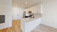 Located at 2314 Berryhill Rd in Charlotte, NC, this thoughtfully designed one-bedroom, one-bathroom unit offers a clean, modern aesthetic throughout its single-floor layout. Light wood-style luxury vinyl plank flooring runs continuously across the space, creating a cohesive and contemporary feel.

The kitchen serves as a central highlight, featuring crisp white shaker cabinetry with black hardware, a herringbone tile backsplash, quartz countertops, and a peninsula with an undermount sink and matte black faucet. Stainless steel appliances, including a refrigerator, range, and microwave, complete the well-appointed cooking space. Recessed lighting overhead keeps the area bright and functional.

The entryway provides convenient closet storage and is accented by paneled white doors with black hardware, maintaining a consistent design language throughout. The bedroom offers a comfortable, private retreat with a ceiling fan, natural light from a window with blinds, and clean white walls that enhance the sense of openness.

The bathroom is finished with classic white subway tile surrounding a soaking tub and shower combo, complemented by light flooring and minimalist fixtures. The overall palette of whites and natural wood tones gives the space a fresh, move-in-ready appeal ideal for those seeking a well-designed home in the Charlotte area.