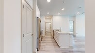 This well-designed single-floor residence offers 2 bedrooms and 3 bathrooms within a thoughtfully arranged layout. The kitchen serves as a central highlight, featuring a large granite-topped peninsula with an undermount sink, white shaker cabinetry extending to the ceiling, and a full suite of stainless steel appliances including a French door refrigerator, electric range, built-in microwave, and dishwasher. Light wood-style luxury vinyl plank flooring runs throughout the kitchen and living areas, contributing to a clean, contemporary aesthetic.

The living room is bright and airy, benefiting from multiple windows that invite natural light and views of the surrounding exterior. A ceiling fan adds both function and style. The primary bedroom is a comfortable, well-proportioned retreat finished with plush carpeting, dual windows, a ceiling fan, and access to a dedicated walk-in closet equipped with dual hanging rods and shelving. The second bedroom also features soft carpeting and neutral white walls.

The bathrooms are finished with white vanities and tile surround tub-shower combinations. Recessed lighting throughout maintains a clean, modern ambiance across the entire unit.