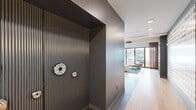 Located at 4557 Laclede Ave in St. Louis's vibrant Central West End neighborhood, this thoughtfully designed single-floor space blends contemporary architecture with warm, curated interiors. The entry corridor makes an immediate impression with its dramatic dark-ribbed accent wall, large-format tile flooring, and sleek modern hardware, setting a sophisticated tone before opening into the main areas.

The lounge area is a standout feature, anchored by rich cognac leather sectional seating, a classic Eames lounge chair, and a textured area rug over light hardwood floors. A textured acoustic ceiling adds depth overhead, while floor-to-ceiling sliding glass doors span an entire wall, flooding the space with natural light and providing seamless access to a landscaped outdoor courtyard furnished for social gatherings.

A low-profile natural wood credenza with an oversized wall mirror adds a refined, functional element to the lounge, complemented by sheer copper-toned drapery that softens the abundant natural light.

The kitchenette and bar area is equally polished, featuring a stone-topped island clad in teal glazed tile, warm wood cabinetry, globe pendant lighting, and mirrored backsplash accents. A vibrant, large-scale graphic mural enlivens the connecting corridor, adding an artistic focal point throughout the space.