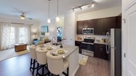 This single-floor residence offers a thoughtfully designed layout with a seamless blend of modern finishes and classic design elements throughout. The open-concept kitchen is a standout feature, equipped with stainless steel appliances, rich dark cabinetry, granite countertops, and a central island with seating — ideal for both cooking and entertaining. Pendant lighting and track lighting illuminate the space, which flows naturally into the living area, where crown molding, a ceiling fan, and wood-look flooring create a refined yet comfortable atmosphere.

The bedrooms are generously proportioned, each featuring plush carpeting, ceiling fans, and natural light from well-dressed windows with decorative curtains. One bedroom includes a walk-in closet, providing excellent storage. The primary bathroom is equipped with a double-sink granite vanity, offering ample counter space, while a second full bathroom mirrors the same quality with a single granite vanity and a shower-tub combo. Dark cabinetry in both bathrooms complements the overall design palette. Throughout the residence, consistent use of granite, dark wood tones, and neutral wall colors creates a cohesive and elegant aesthetic.