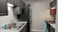 This single-story, one-bedroom, one-bathroom residence at Sawgrass offers a well-organized layout designed for comfortable everyday living. The entryway opens onto dark wood-style flooring that extends through the main living areas, creating a sleek and cohesive aesthetic throughout. The living room is generously proportioned, featuring neutral gray walls, clean white baseboards, and a sliding glass door that leads to a private balcony overlooking the surrounding community — allowing for abundant natural light to fill the space.

The galley-style kitchen is thoughtfully equipped with dark espresso cabinetry, granite-style countertops, a stainless steel double-basin sink, and black appliances including a refrigerator, dishwasher, and range. The kitchen opens via a pass-through, maintaining a connected feel with the rest of the unit.

The bedroom is a comfortable retreat, featuring plush wall-to-wall carpeting, a ceiling fan with light fixture, and a large window that brings in natural light while offering views of the exterior landscape. A dedicated closet provides practical storage.

The bathroom is finished with a granite-style vanity countertop, dark wood cabinetry, a tub-shower combination, and a large mirror, all rendered in a clean, contemporary palette. Additional storage is accessible via a dedicated closet area off the hallway, rounding out this functional and attractive residence.