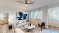 Located at 6615 Waterfront Crossing in Greenacres, FL, this one-bedroom, one-bathroom residence offers a thoughtfully designed single-floor layout with modern finishes and a bright, airy ambiance throughout. Light wood-tone flooring flows seamlessly across all rooms, complementing the crisp white walls and creating a cohesive, contemporary aesthetic.

The open-concept living room is generously proportioned, featuring large windows with horizontal blinds that invite abundant natural light, a ceiling fan with integrated lighting, and ample space for comfortable seating and entertainment. The adjacent kitchen is well-appointed with light wood cabinetry, stainless steel appliances including a refrigerator, range, and microwave, and a spacious island with a quartz countertop and double sink — ideal for both cooking and casual dining. Pendant lighting adds a stylish finishing touch.

The bedroom is a comfortable retreat, offering natural light through a large window, a ceiling fan, and sufficient space for a full furniture arrangement. A dedicated closet provides practical storage. The bathroom features a full tub-shower combination with clean white tile surround, complemented by a quartz vanity surface and wood-tone flooring. A hallway connects the rooms efficiently, completing this well-organized and modern residential layout.