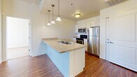 Located at N Harold St in Salt Lake City, Utah, this single-story unit offers a well-designed, functional layout with a clean, contemporary aesthetic throughout. The kitchen serves as a central feature, anchored by a peninsula with a light granite-style countertop, double stainless steel sink, and pendant lighting overhead. White cabinetry lines the walls, complemented by stainless steel appliances including a refrigerator, range, microwave, and dishwasher. Wood-style hard flooring extends through the kitchen and living areas, adding warmth and visual continuity.

The living area flows naturally from the kitchen, bathed in natural light from large windows fitted with horizontal blinds. The bedrooms feature neutral-toned carpet and generous windows that bring in ample daylight while offering outdoor views. The rooms maintain a bright, open feel with clean white walls and simple, practical finishes.

Two full bathrooms are present, each featuring granite-style vanity countertops, white cabinetry, a large mirror with overhead lighting, and a tub-shower combination. Light-toned flooring ties the bathrooms together with the rest of the unit's cohesive design. Overall, the space presents a tidy, move-in-ready environment with consistent finishes throughout.
