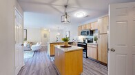 This thoughtfully designed 2-bedroom, 2-bathroom residence offers a functional and comfortable single-floor layout. The open-concept kitchen, dining, and living area serves as the heart of the home, featuring wood-look flooring throughout. The kitchen is equipped with stainless steel appliances, light wood cabinetry, a white subway tile backsplash, granite countertops, and a central island with an additional prep sink and pendant lighting. A dedicated dining nook adjacent to the kitchen provides a defined space for meals, highlighted by a modern geometric chandelier. The living room is bright and welcoming, with crown molding and a sliding glass door that invites natural light and offers access to an outdoor area. Both bedrooms are carpeted and feature neutral tones; the primary bedroom includes a spacious closet, while the secondary bedroom benefits from a natural light-filled window. Each bathroom is finished with light tile flooring, granite-topped vanities, and warm wood cabinetry — one featuring a stand-up glass-enclosed shower. Additional conveniences include an in-unit laundry area and a dedicated closet for extra storage.