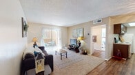 Located at 2000 E River Rd in Tucson, Arizona, this single-floor residence offers a well-organized layout designed for comfortable everyday living. The living room serves as the heart of the home, featuring plush carpeting, a textured ceiling, and a large sliding glass door with vertical blinds that opens to a private outdoor patio, filling the space with abundant natural light and providing a seamless indoor-outdoor connection.

Adjacent to the living room, the dining area features warm hardwood-style flooring and a ceiling fan with light fixture, creating an inviting space for meals. The galley-style kitchen runs parallel to the dining area and is outfitted with rich dark wood cabinetry, light countertops, a full suite of appliances including an electric range and dishwasher, and durable hardwood-style flooring that ties the space together.

The residence includes two carpeted bedrooms, each with vertical-blind windows that invite natural light and offer a calm, restful atmosphere. The bathroom features a vanity with an integrated sink and separate access to a full tub and shower, finished with clean, neutral tones throughout. The overall aesthetic of the home is warm and functional, with a neutral color palette and consistent finishes that create a cohesive, welcoming environment.