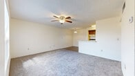 This single-floor unit offers a practical and well-organized layout designed for comfortable everyday living. The spacious living area is carpeted and topped with a textured ceiling, featuring a ceiling fan with light fixture that provides both airflow and ambient lighting. The open layout flows seamlessly toward the kitchen, which is separated by a peninsula-style breakfast bar — ideal for casual dining or additional counter space.

The galley kitchen is well-equipped with warm wood-toned cabinetry, a double sink, white appliances including a refrigerator and range, a dishwasher, and hard surface flooring that contrasts nicely with the carpeted living spaces. A pendant light above the kitchen area adds a functional accent.

The bedrooms are generously proportioned, each featuring plush carpet, neutral walls, and standard closet access. One bedroom benefits from a large window fitted with horizontal blinds, allowing natural light to filter in while maintaining privacy.

The bathroom includes a full-size tub and shower combo with clean white surroundings, wood-look flooring, and warm wood cabinetry overhead. Throughout the unit, consistent neutral tones and textured ceilings create a cohesive, understated aesthetic that provides a blank canvas for personalization.