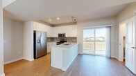 This thoughtfully designed three-story home offers a well-organized layout spanning three distinct floors. The ground level features a garage with a concrete floor and interior staircase access, providing convenient parking and additional storage space. Carpeted stairs with clean white railings connect the levels throughout.

The main living floor hosts an open-concept kitchen and living area bathed in natural light. The kitchen is outfitted with white shaker-style cabinetry, a gray subway tile backsplash, stainless steel appliances including a range, microwave, and refrigerator with ice maker, and a central island with a sink and quartz-style countertops. A sliding glass door opens to a balcony with outdoor views, seamlessly extending the living space.

The upper floor is dedicated to the bedrooms, including a generously sized primary suite with vaulted ceilings, a ceiling fan, plush carpet flooring, and a walk-in closet featuring built-in wire shelving and a window with neighborhood views. The additional bedrooms are bright and well-proportioned, also featuring carpet, ceiling fans, and multi-pane windows. Each of the three bathrooms is finished with white cabinetry, framed mirrors, tile surrounds, and wood-look flooring, maintaining a cohesive modern aesthetic throughout the home.