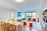 Located at 1232 Boylston St in Boston's vibrant Fenway neighborhood, this modern 2-bedroom, 1-bathroom residence offers a thoughtfully designed single-floor layout with a bright, contemporary aesthetic throughout. The open-concept living and dining area is a standout feature, anchored by expansive floor-to-ceiling windows that flood the space with natural light and offer views of the surrounding cityscape and tree-lined street. Light hardwood floors run throughout, complementing the crisp white walls.

The kitchen is seamlessly integrated into the living area and features light wood cabinetry, white upper cabinets, stainless steel appliances including a refrigerator and oven, and a clean-lined countertop — ideal for both everyday cooking and entertaining. A large white dining table with woven wood chairs connects the kitchen to the living space.

The living room offers generous seating, a glass coffee table, and a leaning bookshelf unit, creating a functional yet stylish area for relaxing. The primary bedroom benefits from large corner windows with urban views, while the bathroom is finished with marble-style tile, a soaking tub with shower, a floating wood vanity, and a conveniently stacked in-unit washer and dryer. A closet completes the layout.