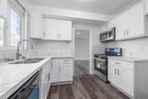 Located at 9601 Crenshaw Blvd in Inglewood, CA, this 2-bedroom, 1-bathroom single-floor residence offers a clean, modern aesthetic with thoughtfully updated finishes throughout. Wide-plank wood-look flooring flows seamlessly across all rooms, complemented by soft gray walls and crisp white trim that create a bright, cohesive feel.

The living room is generously proportioned, bathed in natural light through large windows dressed with sheer curtains that frame outdoor greenery views. A sliding glass door provides additional light and outdoor access. The kitchen features white shaker cabinetry, marble-look quartz countertops, stainless steel appliances including an over-the-range microwave and gas range, and a teal dishwasher that adds a pop of color. A subway tile backsplash adds a refined touch.

Both bedrooms are comfortably sized, each featuring ceiling fans with integrated lighting, multiple windows with vertical blinds, and excellent natural light. The primary bedroom includes a closet with built-in shelving. The bathroom is clean and functional, finished in white with a soaking tub, a wall-mounted vanity, a mirrored medicine cabinet, and a natural light window. A connecting hallway links the rooms efficiently, completing this well-organized and move-in-ready home.