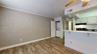 Located in Glendale, Arizona, this two-bedroom, one-bathroom unit offers a practical and efficient single-floor layout. The living area features wood-look plank flooring, textured walls, and a textured ceiling, creating a warm and understated ambiance. A half-wall pass-through connects the living space to the kitchen, which is outfitted with gray cabinetry, a light quartz-style countertop, black appliances including an electric range and refrigerator, and an overhead exhaust vent. The kitchen's clean, functional design maximizes the use of available space. A convenient in-unit stacked washer and dryer is tucked into a dedicated closet off the main living area, adding everyday practicality. Both bedrooms are carpeted and feature textured walls, with windows that allow natural light to filter in. The primary bedroom includes a closet and direct visual access to the full bathroom, which is outfitted with a shower-tub combination, toilet, and vanity with storage. A hallway linen closet provides additional storage between the bedrooms and bathroom. Wood-look flooring continues through the hallway, tying the common areas together cohesively. This well-organized unit delivers essential amenities in a compact, easy-to-navigate floor plan.