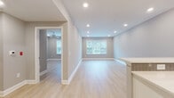 135 Stevens Ave is a thoughtfully designed single-floor residence that combines contemporary finishes with a clean, open layout. Light hardwood flooring runs throughout the main living areas, complementing the soft neutral gray walls and crisp white trim that give the space a bright, cohesive feel. The open-concept living and dining area is bathed in natural light from large windows, while recessed lighting overhead ensures the space remains well-lit at all hours. A ceiling fan adds comfort to the adjacent room, which also enjoys outdoor views through its own window.

The kitchen is a standout feature, outfitted with white shaker cabinetry, gray subway tile backsplash, and sleek quartz countertops extending to a peninsula with pendant lighting above. Stainless steel appliances — including a gas range, microwave, and refrigerator — complete the modern setup, with a matte black faucet adding a sharp design contrast.

The bedrooms offer generous proportions with the same light hardwood floors, neutral tones, and ample natural light. Each room is equipped with ceiling fans and well-placed outlets for functionality.

The bathroom presents a bold contrast with dark tile flooring, a white vanity topped with a black granite countertop, a large mirror, matte black fixtures, and a full tub-shower combination framed by classic white tile — creating an elegant, modern aesthetic throughout.