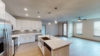 Located in Houston, TX (77084), this thoughtfully designed 3-bedroom, 2-bathroom residence features a single-floor layout that maximizes comfort and functionality. The open-concept kitchen is a standout, showcasing crisp white cabinetry, a mosaic tile backsplash, quartz countertops, a large center island with an undermount sink, and a full suite of stainless steel appliances, including a French door refrigerator, range, microwave, and dishwasher. Pendant lighting above the island adds a modern touch, while light wood-look flooring flows seamlessly into the adjacent living area. The living room is bright and airy, featuring a ceiling fan, large windows with blinds, and a glass door that invites natural light throughout. Each bedroom is carpeted for comfort and equipped with a ceiling fan. The bedrooms feature spacious walk-in closets with built-in shelving and hanging rods. The primary bathroom offers a dual-sink vanity with quartz countertops, a large mirror, and direct access to a walk-in closet. The secondary bathroom includes a tiled tub-shower combination and a single vanity. The overall aesthetic is clean and contemporary, with neutral tones and modern finishes creating a welcoming, move-in-ready atmosphere.