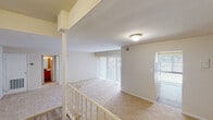 This residential unit offers a practical and comfortable layout across a single floor, designed to maximize functionality and natural light. The entry features a split-level design with a staircase and railing, leading up to the main living area. A coat closet is conveniently located near the front door, providing useful storage from the moment you arrive.

The spacious living room is finished with plush wall-to-wall carpeting and is anchored by a large sliding glass door dressed with vertical blinds, allowing generous natural light to fill the space and offering views of the outdoors. The open layout transitions smoothly between the living and dining areas.

The kitchen is equipped with light wood cabinetry, dark countertops, and white appliances including a gas range and dishwasher. A large window above the kitchen area brings in additional daylight and overlooks the exterior, making it a pleasant workspace. The kitchen features easy-care hard-surface flooring.

The bedrooms are carpeted and well-proportioned, offering clean, neutral walls and ample room for furnishings. Each room benefits from the unit's overall bright, airy palette. The bathroom includes a full-size tub and shower combination with classic white tile surround and chrome fixtures, providing a clean and functional space. Overall, the unit presents a neutral, move-in-ready interior throughout.