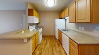 This single-floor unit offers a functional and well-organized layout designed for comfortable everyday living. The open living area is spacious and bright, featuring neutral-toned carpet, textured ceilings, and a sliding glass door that fills the space with natural light and provides outdoor access. A dedicated entryway with a warm wood-toned door leads directly into the main living space, which also features a floor vent for climate control.

The galley-style kitchen is efficiently designed with warm wood cabinetry lining both walls, granite-look countertops, and durable wood-look flooring. White appliances — including a refrigerator, electric range, microwave, and dishwasher — are all included. A breakfast bar with counter seating creates a natural transition between the kitchen and living area.

Two carpeted bedrooms each feature ceiling fans with integrated lighting, blinded windows for natural light and privacy, and easy access to closet space. One bedroom includes a generously sized walk-in closet with built-in shelving and dual hanging rods, providing abundant storage.

The full bathroom is finished with tile flooring, a wood-toned vanity with granite-look countertops, a wall mirror, and a full soaking tub with shower combination.