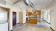 Located at 800 Olive, this one-bedroom, one-bathroom unit showcases a distinctive industrial-chic aesthetic that blends raw architectural elements with modern finishes. Polished concrete floors flow throughout the entire space, providing a cohesive, contemporary foundation. The open-concept living and kitchen area is anchored by an exposed large-diameter ventilation duct that runs prominently across the ceiling, lending an authentic urban loft character.

The well-appointed kitchen is a standout feature, offering warm maple cabinetry, granite countertops, a central island with additional counter seating, and a full suite of stainless steel appliances including a refrigerator, dishwasher, range, and built-in microwave. Track lighting and pendant fixtures illuminate the space efficiently. A floor-to-ceiling glass door opens to the living area, which benefits from natural light through large windows overlooking the surrounding cityscape.

The bedroom is a comfortably sized retreat with clean white walls, concrete flooring, and two generous closets with built-in shelving — providing ample storage. The bathroom features a tiled shower/tub combination and maintains the unit's clean, minimalist palette. Overall, this unit delivers a functional and stylish urban living experience defined by its industrial design sensibility and quality finishes.