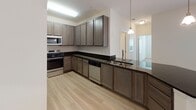 This contemporary apartment boasts a thoughtfully designed layout that maximizes space and functionality. The heart of the home is a sleek, modern kitchen featuring gray cabinetry, black countertops, and stainless steel appliances. The open concept design seamlessly connects the kitchen to the living area, creating an ideal space for entertaining.

The bedrooms are generously sized, with plush carpeting and large windows that allow natural light to flood the space. Ceiling fans add both style and comfort. Built-in closets with wire shelving systems provide ample storage options.

The bathroom continues the modern aesthetic with a floating vanity, large mirror, and wood-look flooring. Throughout the apartment, neutral tones dominate, creating a calm and versatile backdrop for any decor style.

Additional features include a dedicated laundry area with hookups for full-sized appliances, and a utility closet for extra storage. The overall design emphasizes clean lines, practical amenities, and a bright, airy feel, making this apartment an attractive option for contemporary urban living.