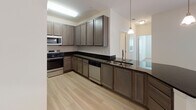 This contemporary apartment boasts a thoughtfully designed layout that maximizes space and functionality. The heart of the home is a sleek, modern kitchen featuring gray cabinetry, black countertops, and stainless steel appliances. The open concept design seamlessly connects the kitchen to the living area, creating an ideal space for entertaining.

The bedrooms are generously sized, with plush carpeting and large windows that allow natural light to flood the space. Ceiling fans add both style and comfort. Built-in closets with wire shelving systems provide ample storage options.

The bathroom continues the modern aesthetic with a floating vanity, large mirror, and wood-look flooring. Throughout the apartment, neutral tones dominate, creating a calm and versatile backdrop for any decor style.

Additional features include a dedicated laundry area with hookups for full-sized appliances, and a utility closet for extra storage. The overall design emphasizes clean lines, practical amenities, and a bright, airy feel, making this apartment an attractive option for contemporary urban living.
