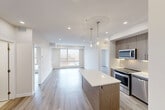 Located on Elbow Drive SW in Calgary, AB, this modern 2-bedroom, 3-bathroom unit offers a well-designed open-concept layout finished with light wood-look flooring and a crisp, neutral palette throughout. The kitchen is a standout feature, outfitted with sleek walnut-toned cabinetry, a full suite of stainless steel appliances including a range, microwave, dishwasher, and refrigerator, and a large central island with a white quartz countertop illuminated by elegant glass pendant lights. The kitchen flows seamlessly into the living area, which is bathed in natural light from a large picture window overlooking the surrounding neighbourhood. Both bedrooms are well-proportioned, featuring generous windows with outdoor views and double-door closets for ample storage. The three bathrooms are finished with warm-toned tile, wood-grain vanity cabinetry, and clean white fixtures, with at least one full bath-and-tub combination. A dedicated laundry room houses a stacked front-load washer and dryer. Three closets and a private balcony complete this thoughtfully laid-out space, making it a functional and stylish urban home in southwest Calgary.